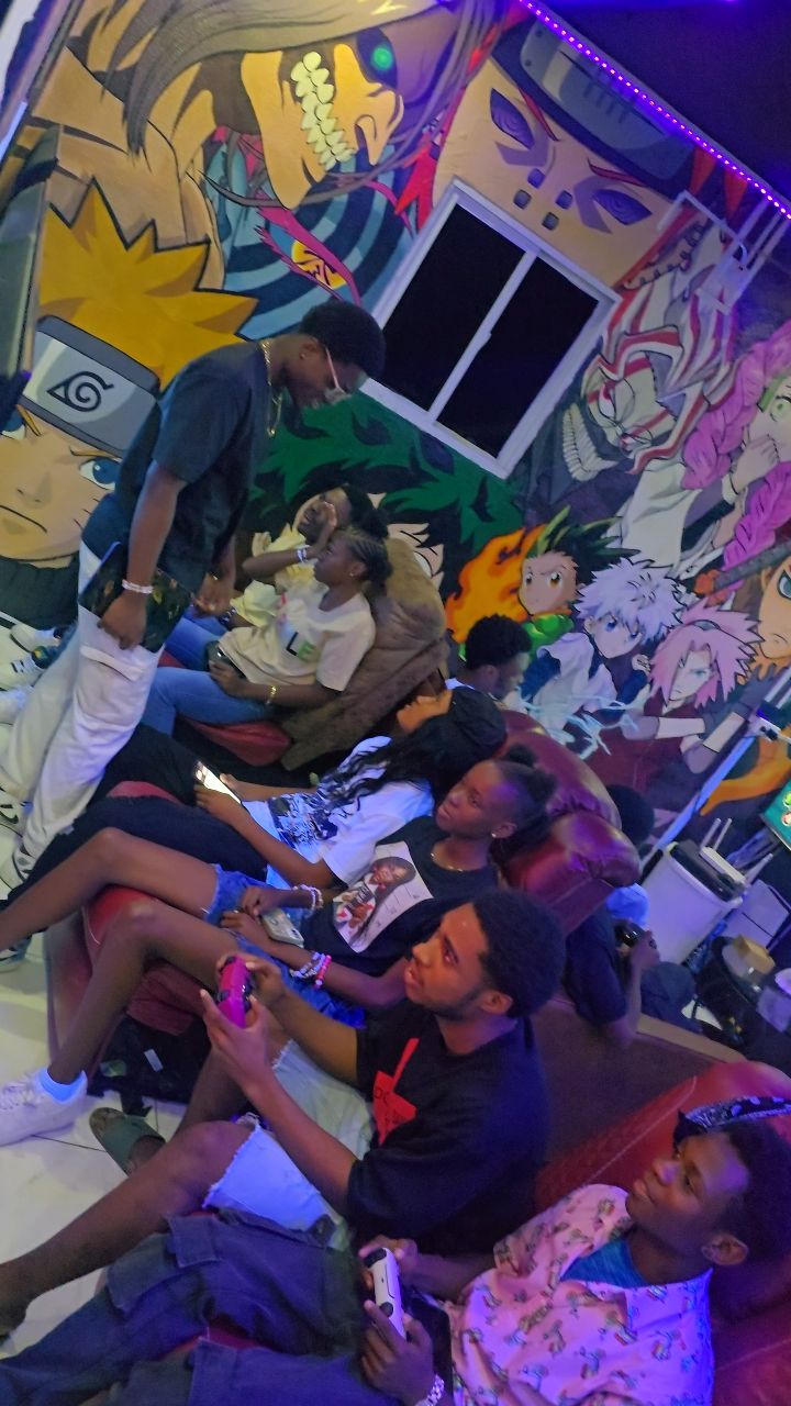 Gamers on couches at Ravenz Realm surrounded by hand-painted anime murals